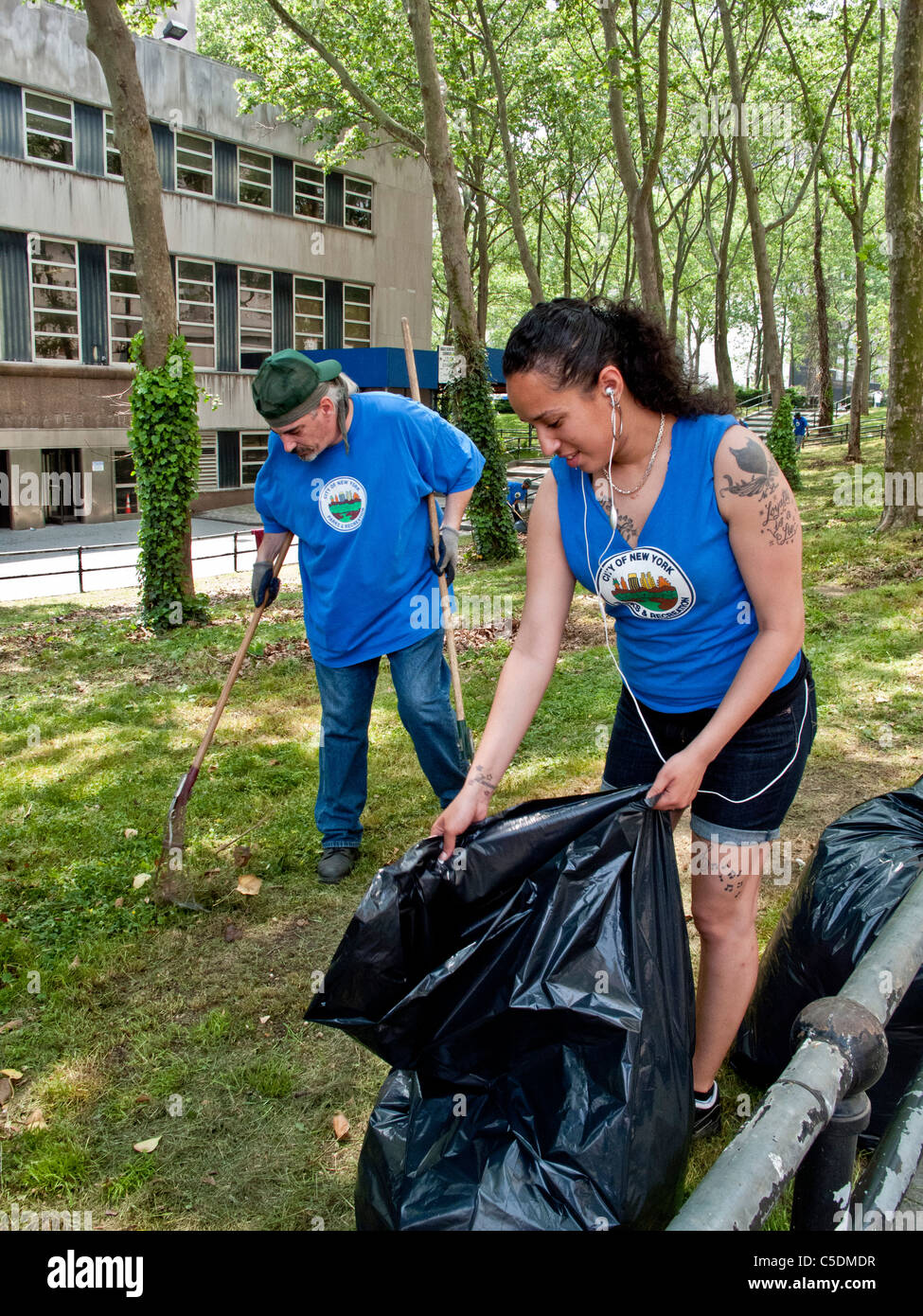 Uniformierte Sanitation Arbeiter, darunter eine tätowierte Frau sammeln Müll in Cadman Plaza, Brooklyn, NY. Stockfoto