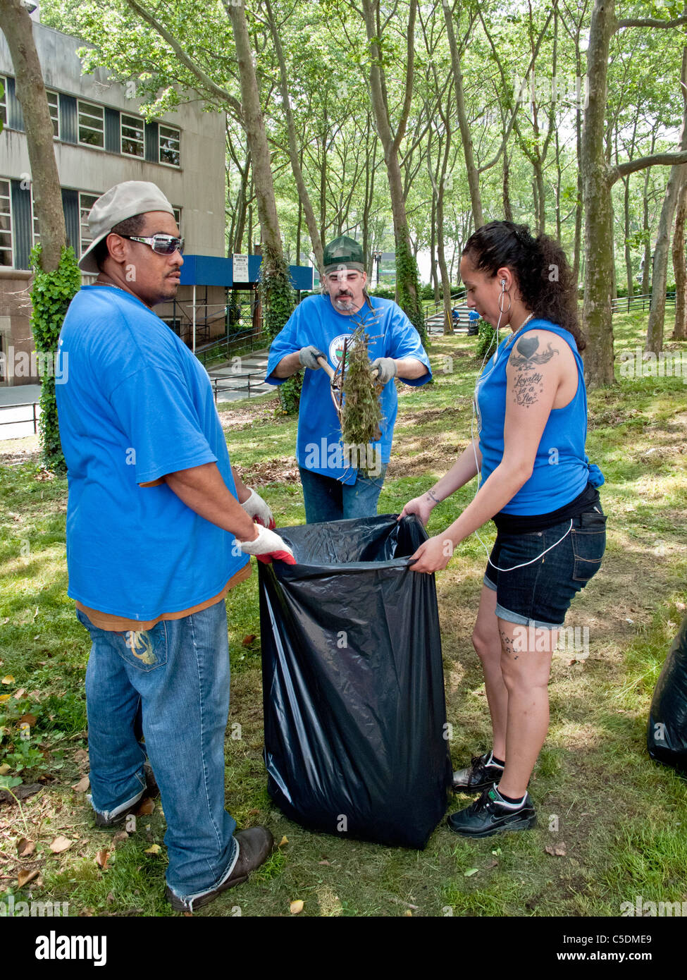 Uniformierte Sanitation Arbeiter, darunter eine tätowierte Frau sammeln Müll in Cadman Plaza, Brooklyn, NY. Stockfoto