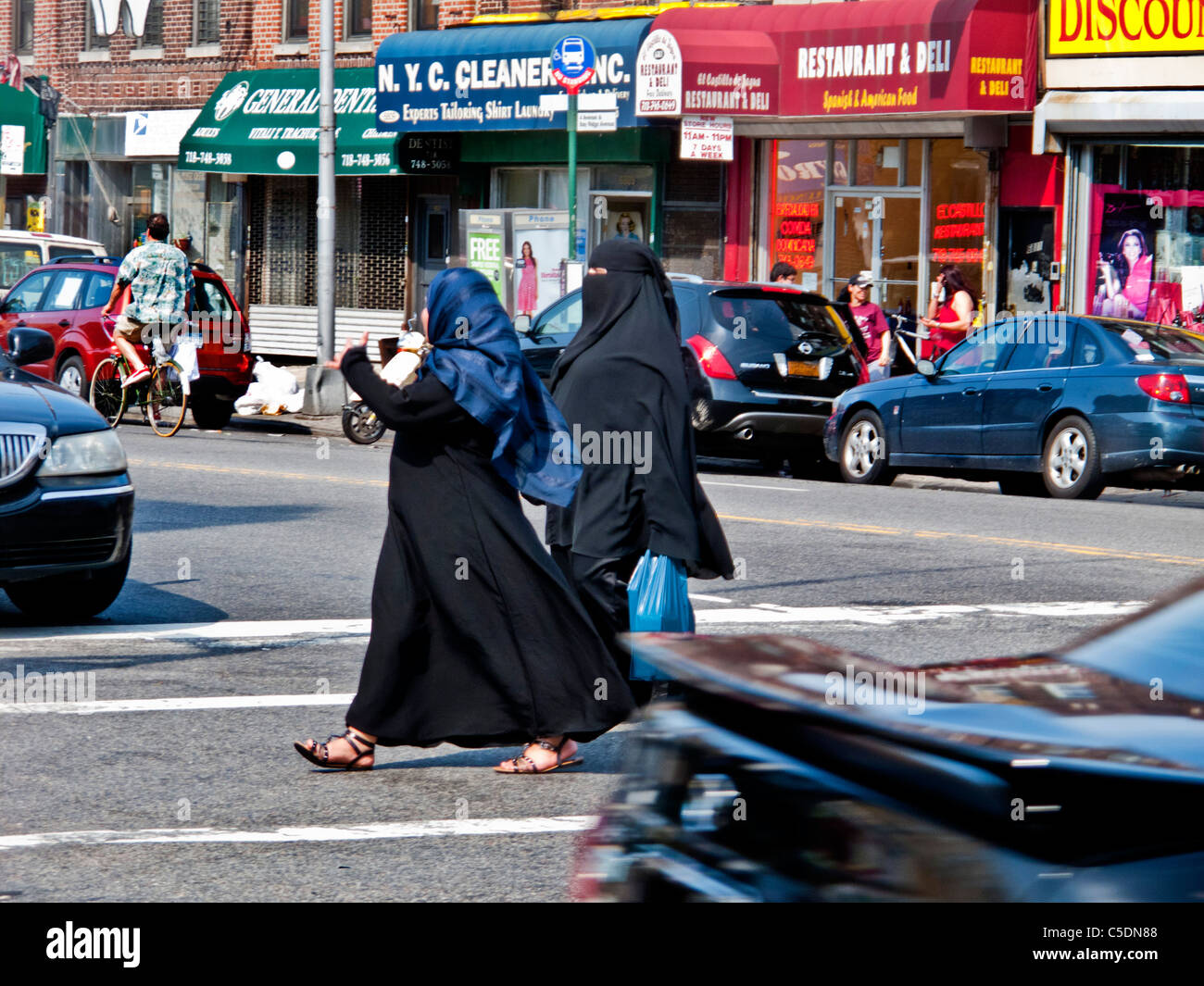 Muslimische Frauen in eine Burka und Kopftuch überqueren eine Straße im Abschnitt 'Little Beirut' Bay Ridge in Brooklyn, New York. Stockfoto