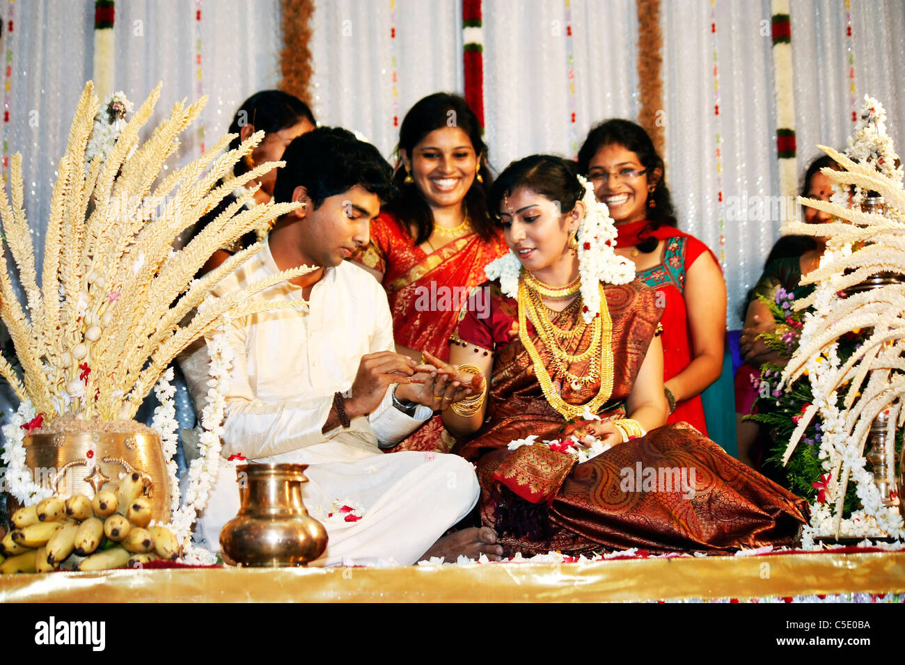 Ein detailliertes Portrait des Bräutigams Platzierung einen Ehering am Finger der Braut während ihre Hindu-Hochzeit ritual Stockfoto