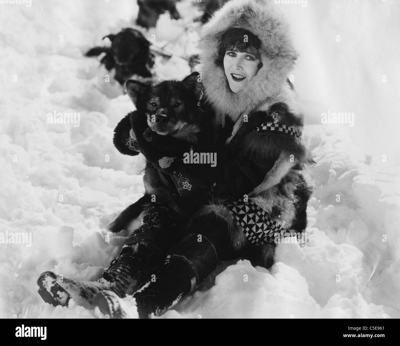 Frau und Hund spielen im Schnee Stockfoto