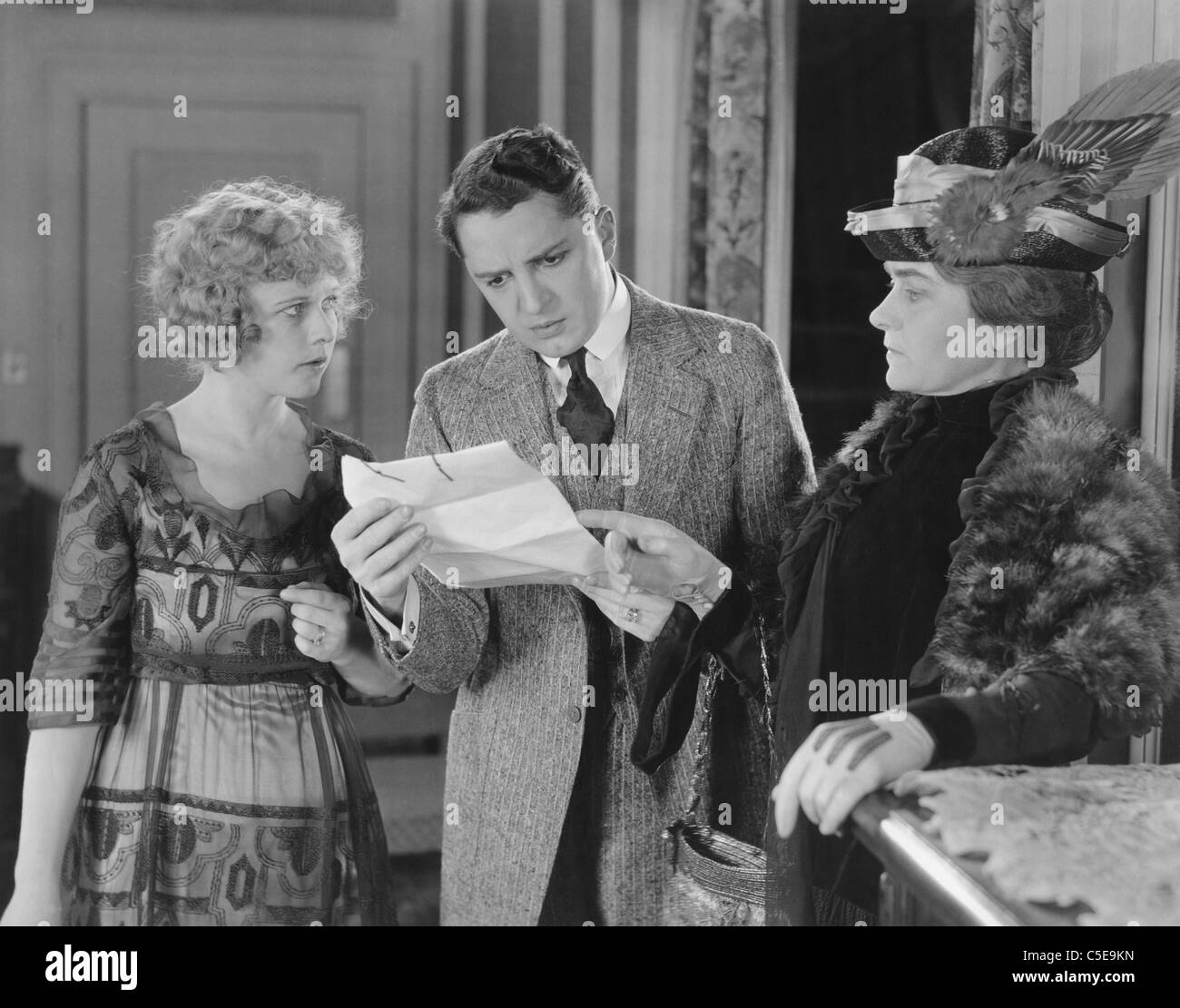 Mann liest Brief mit zwei Frauen über die Schulter schauen Stockfoto