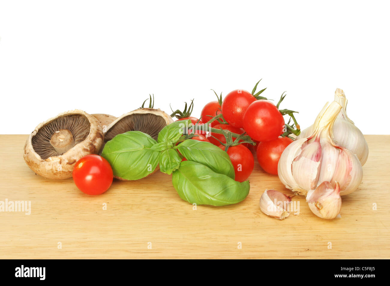Kostenlose Lebensmittelzutaten, Tomaten, Champignons, Basilikum und Knoblauch auf einem Brett aus Holz Essen Vorbereitung Stockfoto
