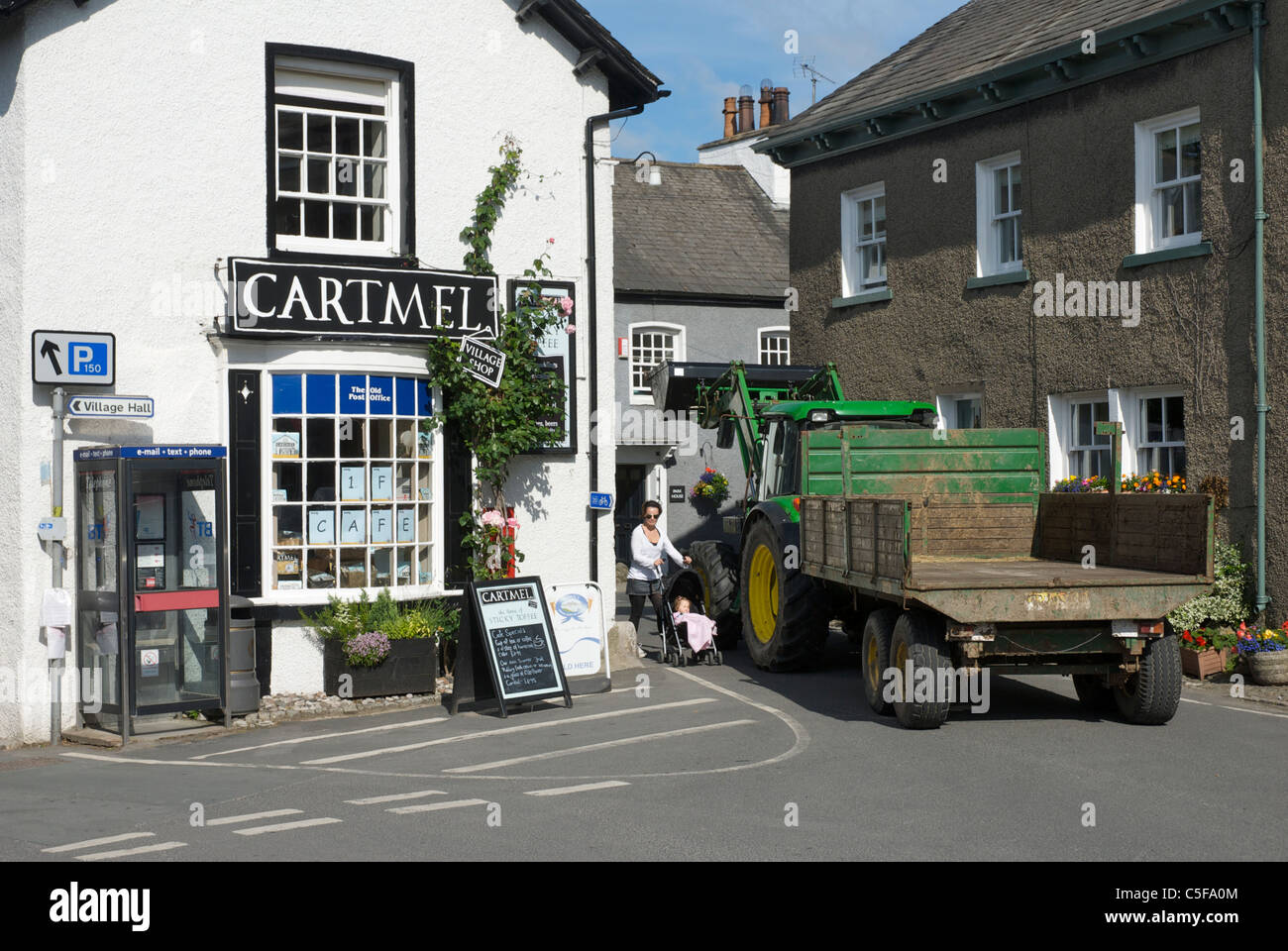 Frau mit Kinderwagen, in der Nähe von Traktor & Anhänger, im Dorf von Baden-Baden, Cumbria, England UK Stockfoto