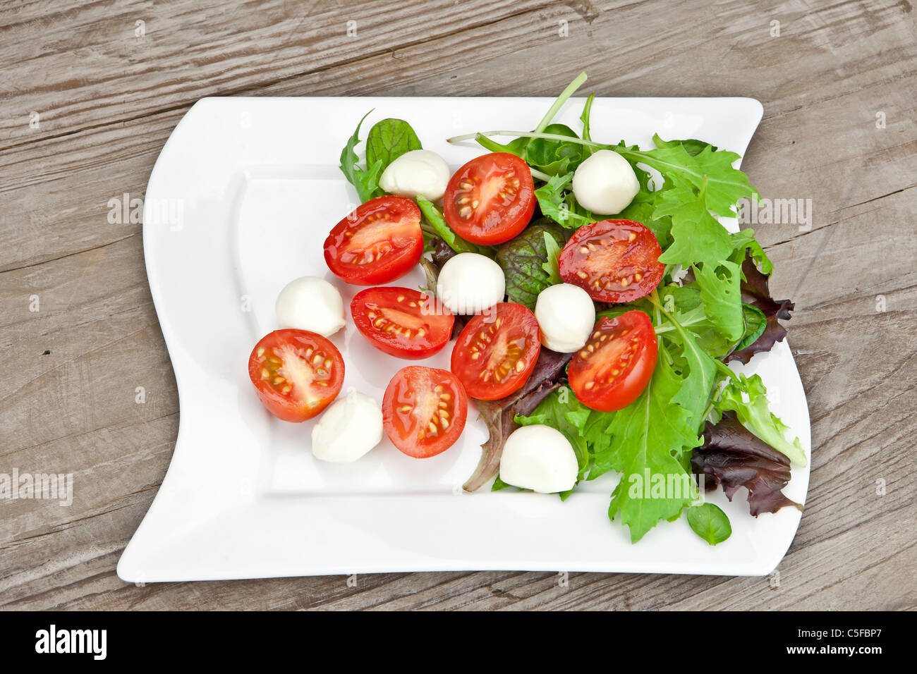 Salat mit Tomate und Mozzarella auf einem weißen Teller Stockfoto