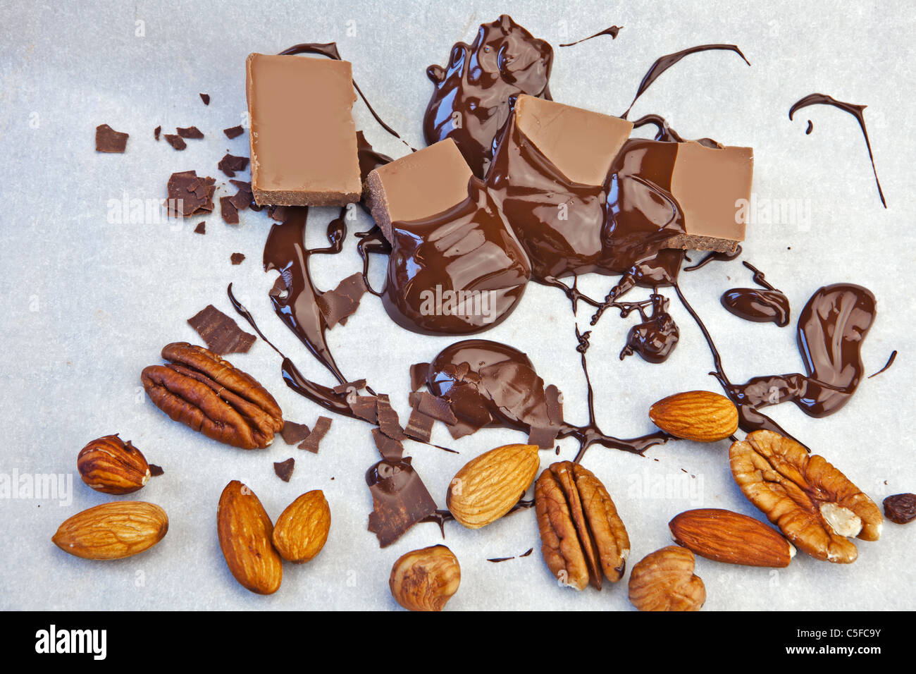 glatte Schokoladenstücke mit Schokoladensauce und Nüssen Stockfoto