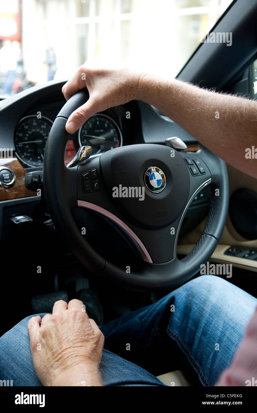 Reife Mans Hände am Lenkrad für BMW Stockfoto