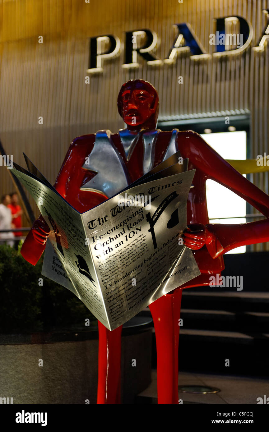 Rot bemalte Statue lesen shopping Broadsheet außerhalb ION Shopping Mall auf der Orchard Road, Singapur Stockfoto