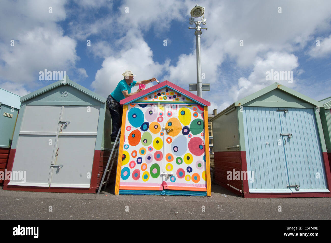 Mann seine Strandhütte in Nichtregelung Farben malen Stockfoto