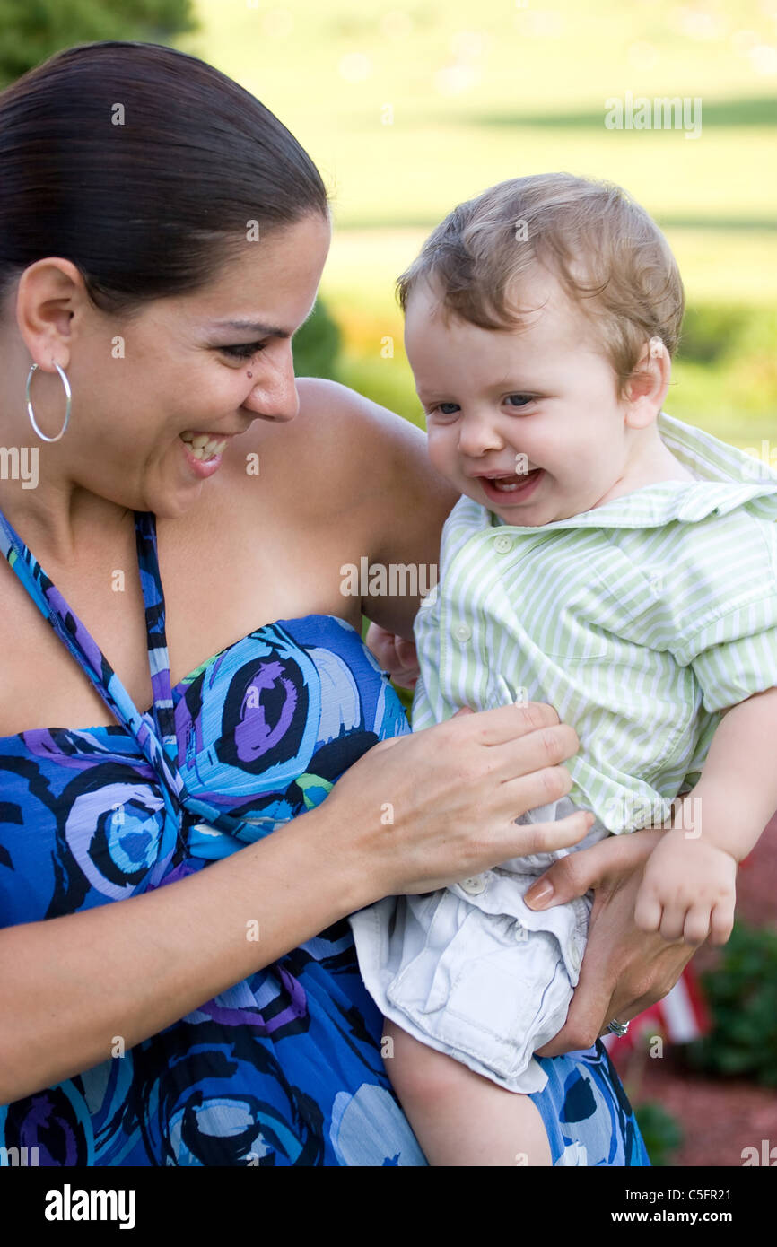 Eine junge Mutter kitzelt ihr Baby glücklich. Stockfoto