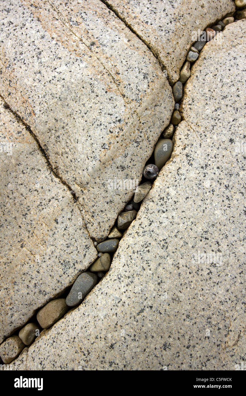 Eingeschlossenen Steinen im Riss in großen glatten Skye weißen Marmorfelsen auf Camas Malag Strand, Isle Of Skye, Schottland, UK Stockfoto