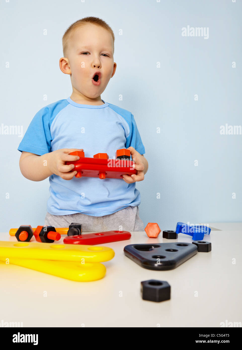 Kleiner Junge spielt mit Plastikspielzeug auf blauem Hintergrund Stockfoto