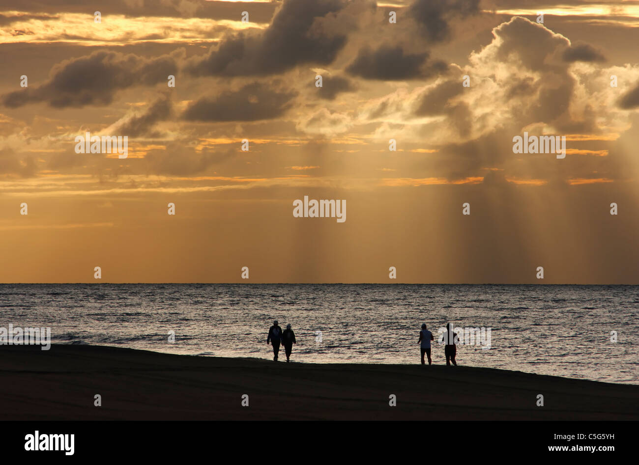 Menschen wandern und Joggen am Strand bei Sonnenuntergang. Maspalomas, Gran Canaria, Kanarische Inseln, Spanien Stockfoto