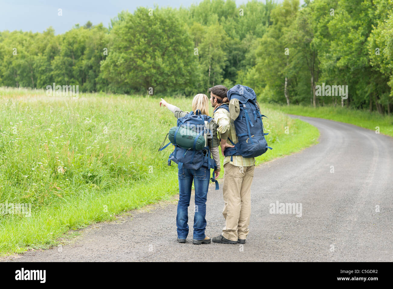 Junges Paar Wanderrucksack trampeln auf Asphalt Straße Landschaft Stockfoto