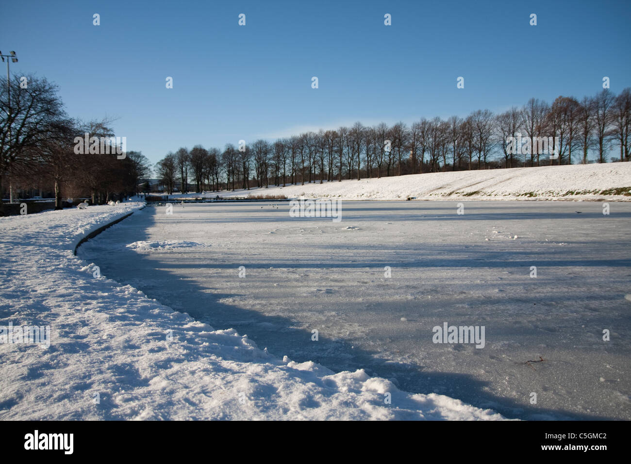 Inverleith Park Teich im Winter, mit Bäumen und blauen Himmel, Schnee und Eis gefroren Stockfoto