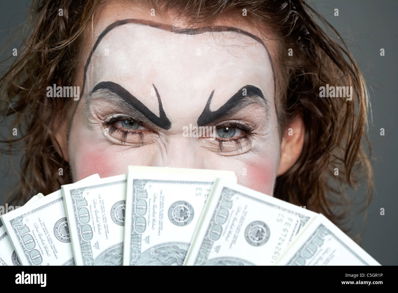 Bemalte Gesicht hinter mehrere Banknoten Stockfoto