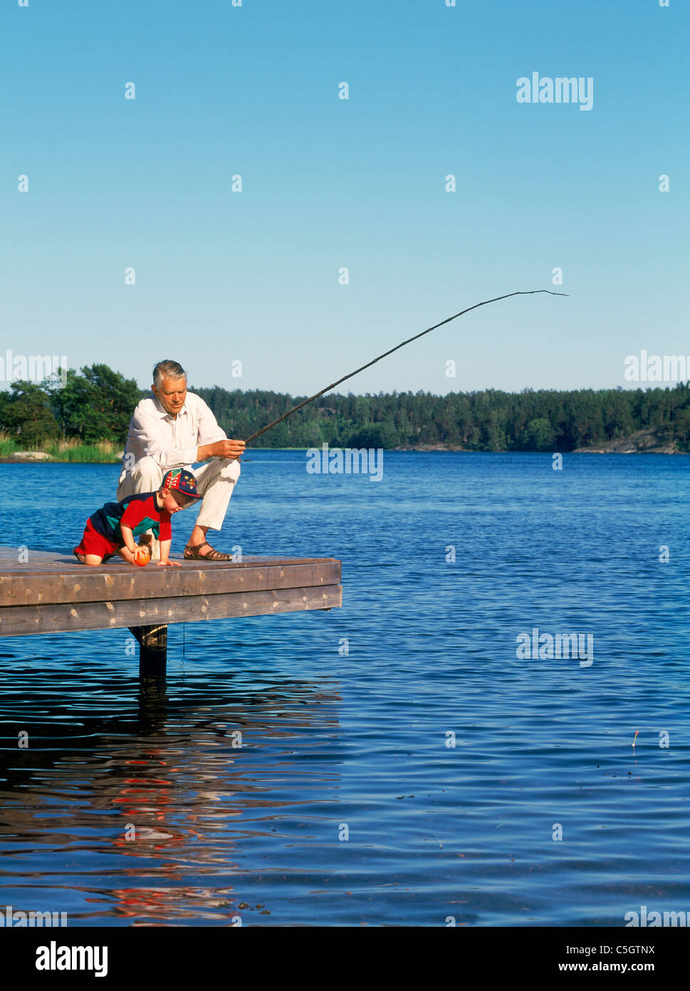 Großvater mit Enkel aus hölzernen Dock entlang Ostsee Küste im schwedischen Sommer Angeln Stockfoto