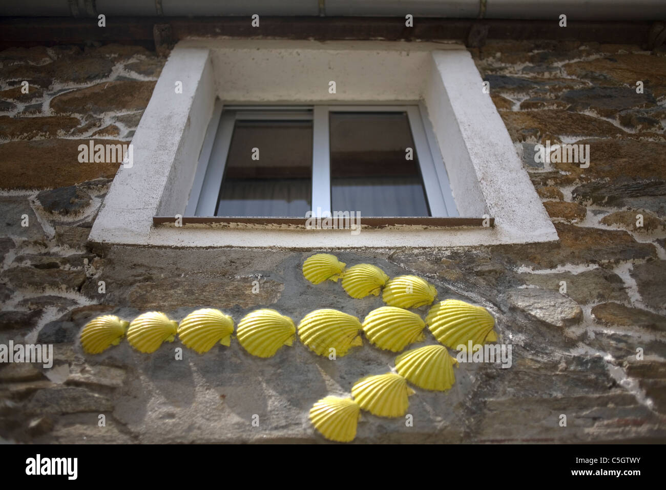 Ein gelber Pfeil aus Jakobsmuscheln in einem Haus zum Pilgern in die französische Lebensart St. James Weg, Galicien, Spanien zu führen. Stockfoto