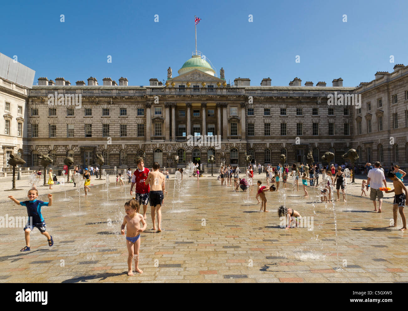 Kinder spielen mit Wasser an einem sonnigen Tag am Somerset House, London, England, Großbritannien, UK Stockfoto