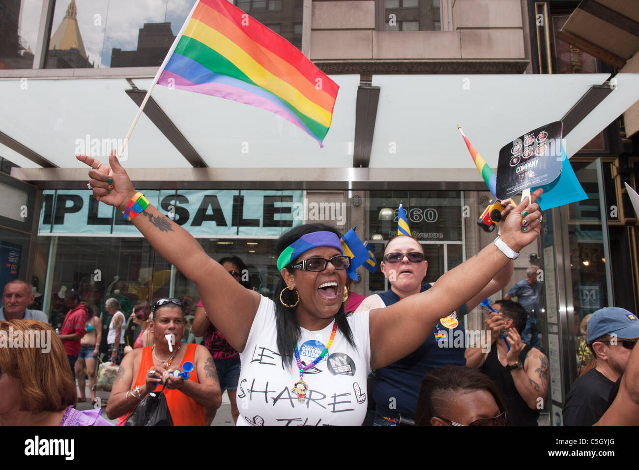 Eine schwarze Frau Jubel wie sie verzichtet auf die Regenbogenflagge während der Gay Pride Parade in New York City. Stockfoto