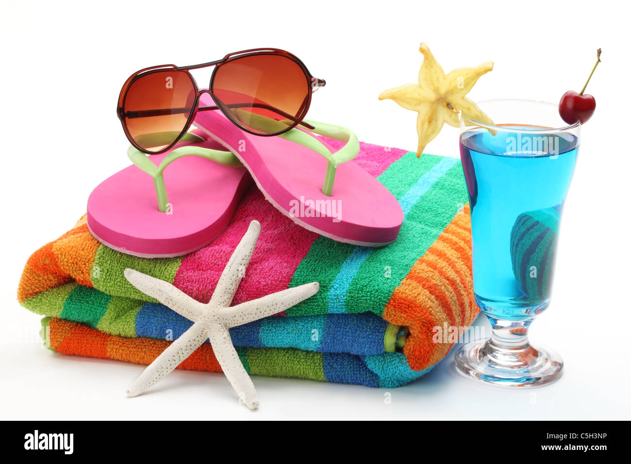 Strandzubehör mit Handtuch, Flip-Flops, Sonnenbrillen und ein Glas Cocktail. Isoliert auf weißem Hintergrund. Stockfoto