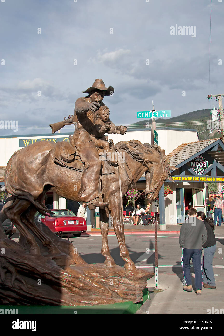 Hier eine kleine Jungs reiten auf einem Pferd in den Armen von einem verwitterten alten Cowboy, Vater oder Großvater vielleicht?, in Jackson Hole, USA. Stockfoto
