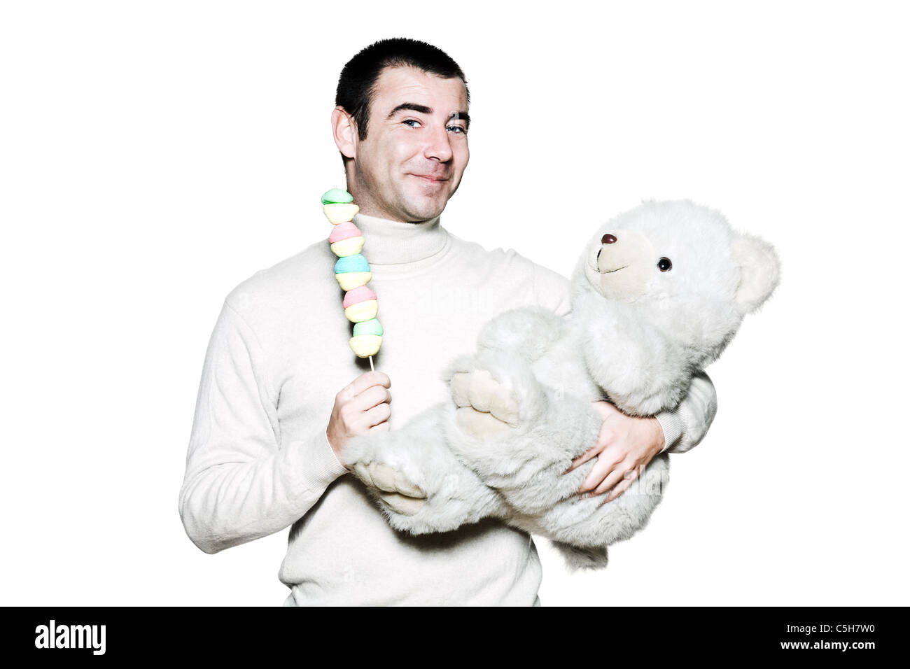 Porträt von einem kindischen reifen Mann mit Spielzeug und Teddybären im Studio auf weißen Hintergrund isoliert Stockfoto
