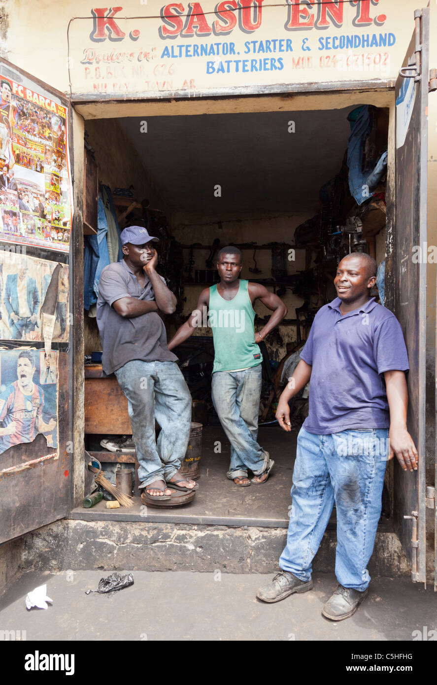 Drei Mechaniker vor K. Sasu ENT. Werkstatt für Lichtmaschine und Batterie, Accra, Ghana Stockfoto