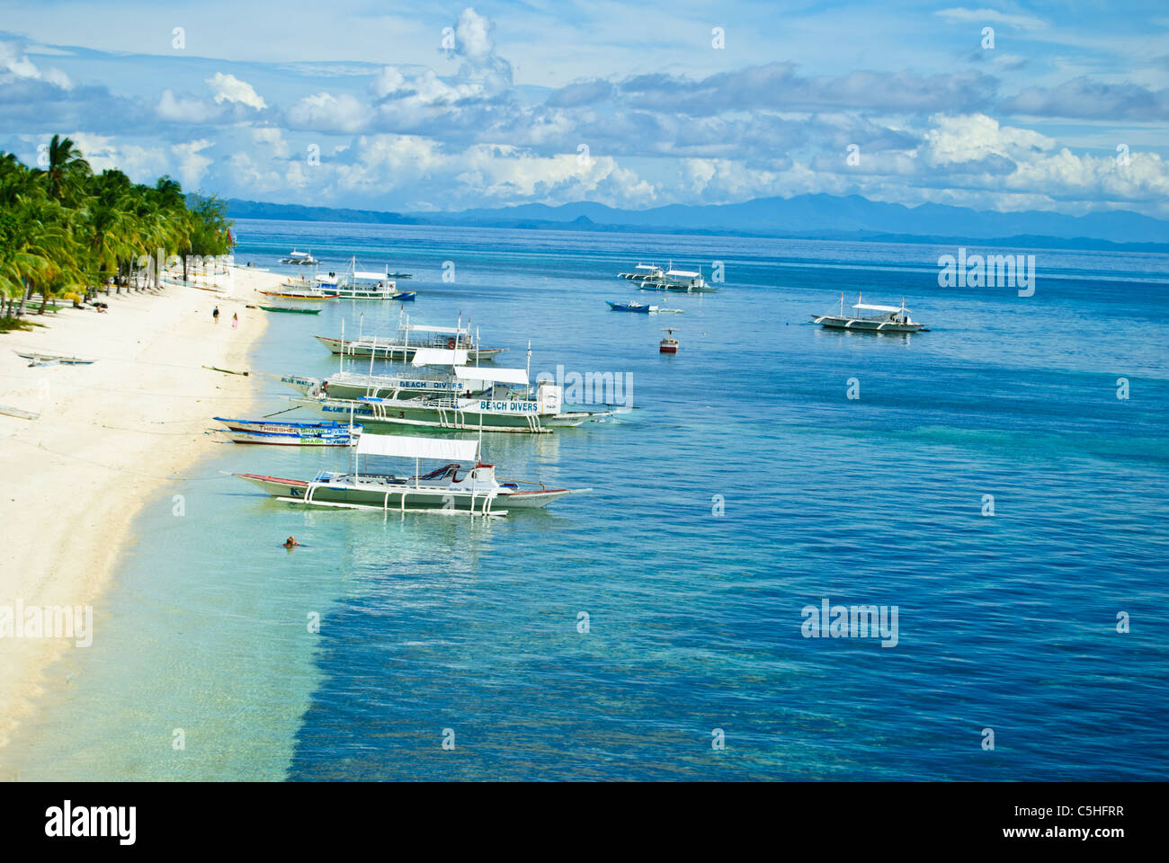 Ausleger als Tauchboote festmachen entlang dem Strand von Malapascua Island Stockfoto