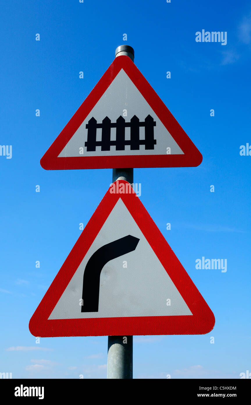Warnschilder, die einen Bahnübergang anzeigen, und Rechtskurve voraus. Blue Anchor, Somerset, England. Stockfoto
