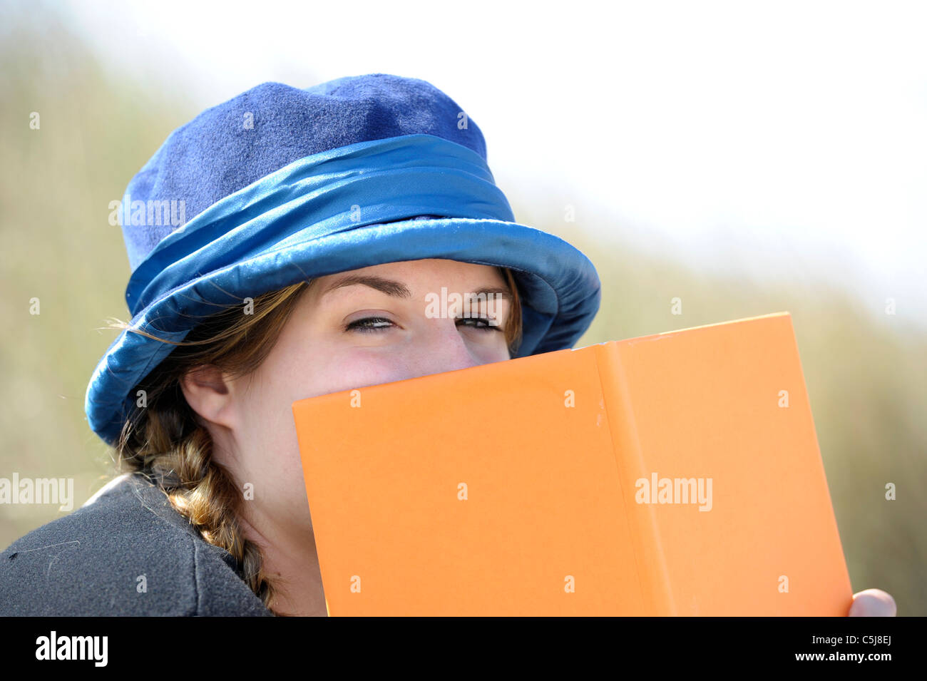 Outdoor Portrait der schönen jungen Frau versteckt sich hinter einem Buch Stockfoto
