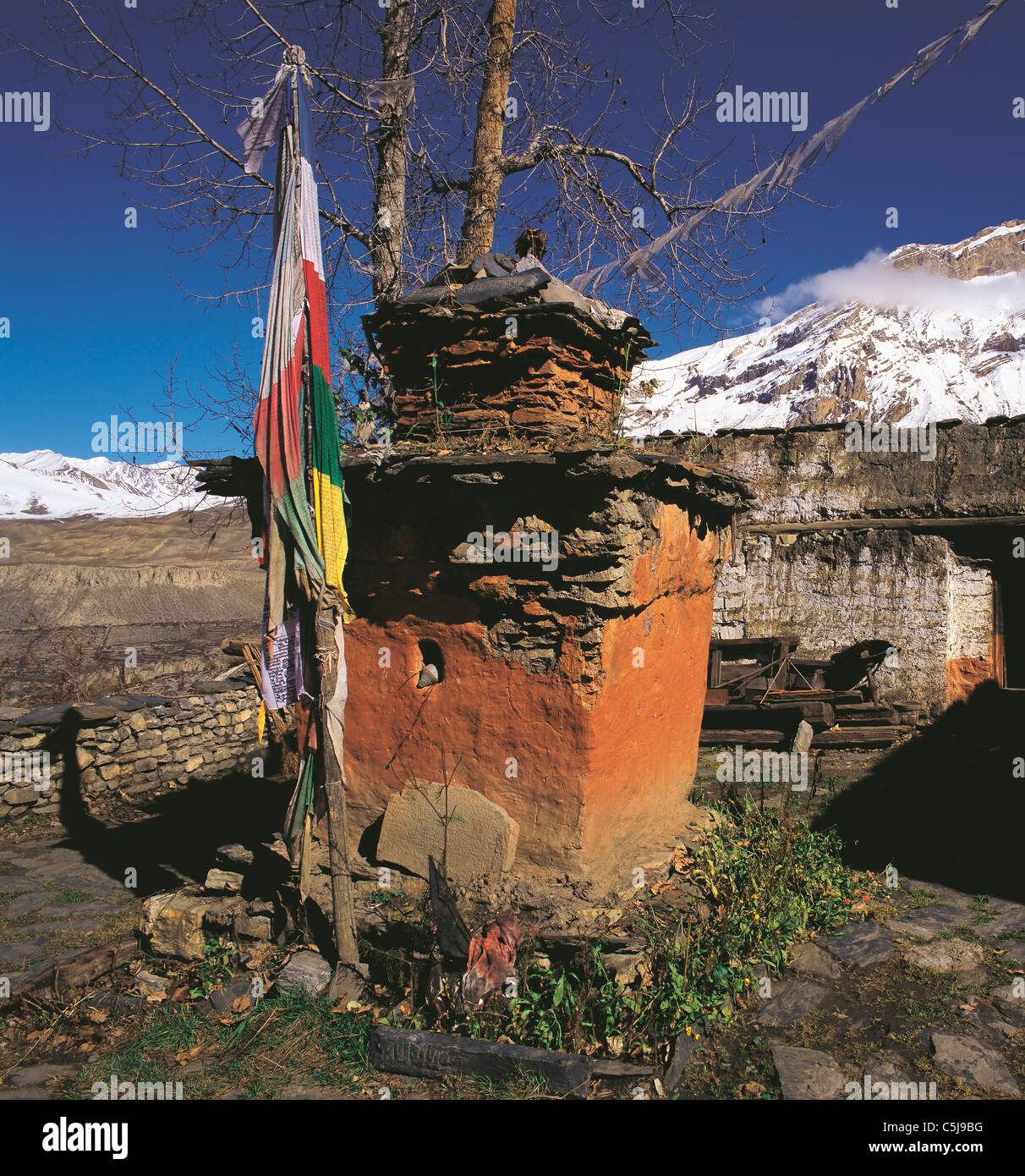 Eine bemalte devotional Objekt oder Chorten innerhalb der Tempelmauer in Muktinath mit Schneeberge sichtbar oben in der Mustang Stockfoto