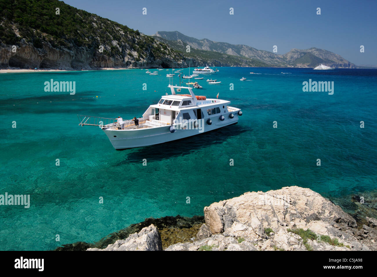 Fähre auf dem transparenten Wasser des Strandes Cala Luna, Cala Gonone, Sardinien Stockfoto