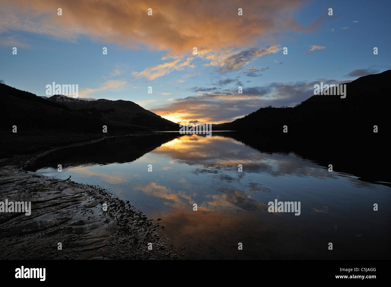 Lebendige Winter Sonnenuntergang und fernen Hügel reflektiert in ruhige Loch Dochart, Perthshire, Schottland Stockfoto