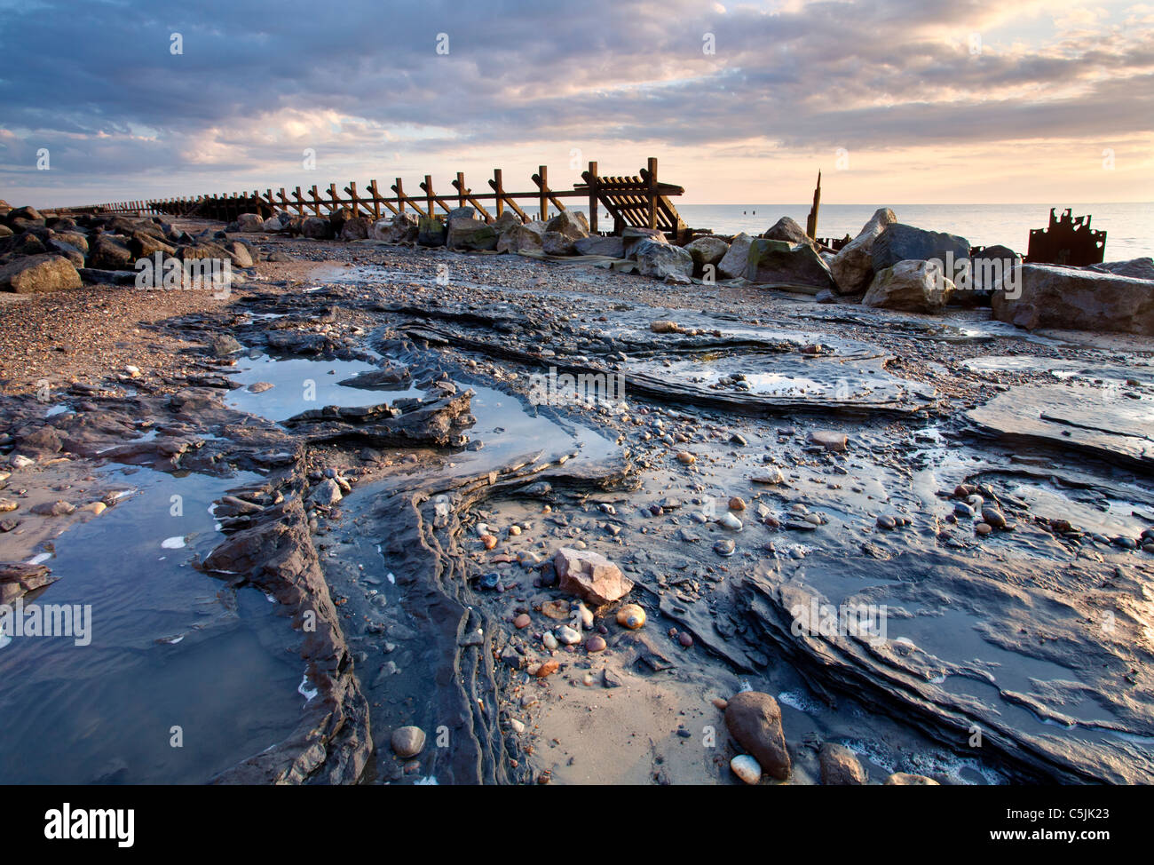 Erstes Licht beleuchtet die verfallenen Küstenschutzes bei Happisburgh an der Küste von Norfolk Stockfoto