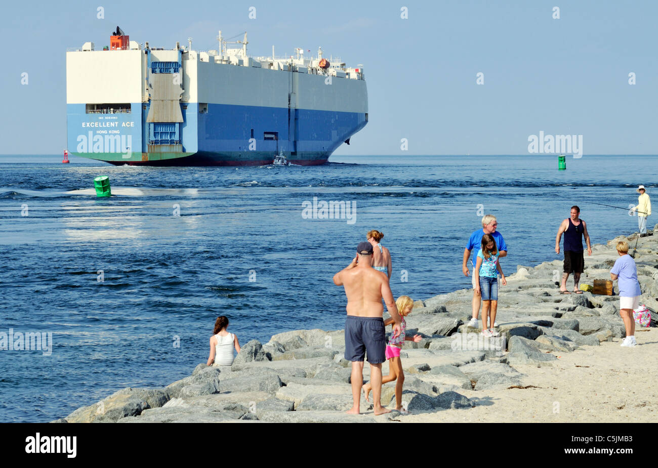 Car carrier Frachtschiff ausgezeichnete Ace Verlassen der Cape Cod Canal in den Schacht für das offene Meer mit Menschen auf der Jetty in Badekleidung zu beobachten. USA Stockfoto