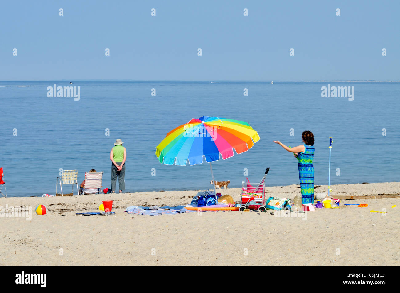 Touristen mit bunten Sonnenschirm an einem Cape Cod-Strand mit Blick auf Cape Cod Bay auf einem sonnigen blauen Himmel Sommertag. USA Stockfoto
