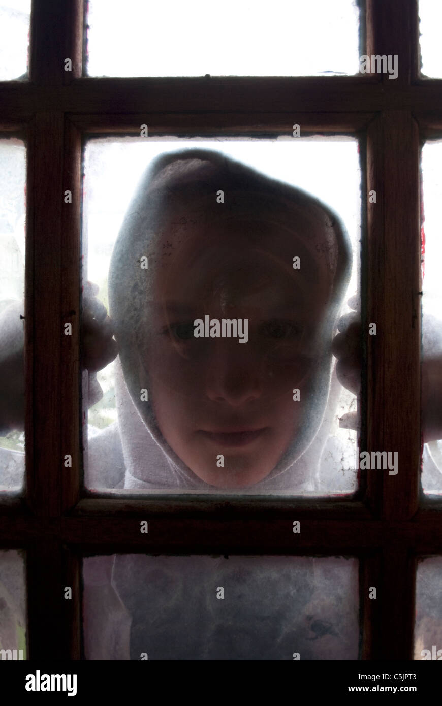 Eine Jugend in einem Hoodie Blick durch ein Fenster in der Tür. Stockfoto