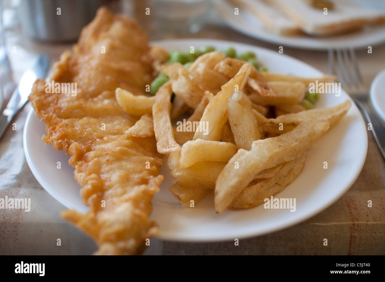 Fish &amp; Chips serviert mit Erbsenpüree auf einem Teller in England. Stockfoto