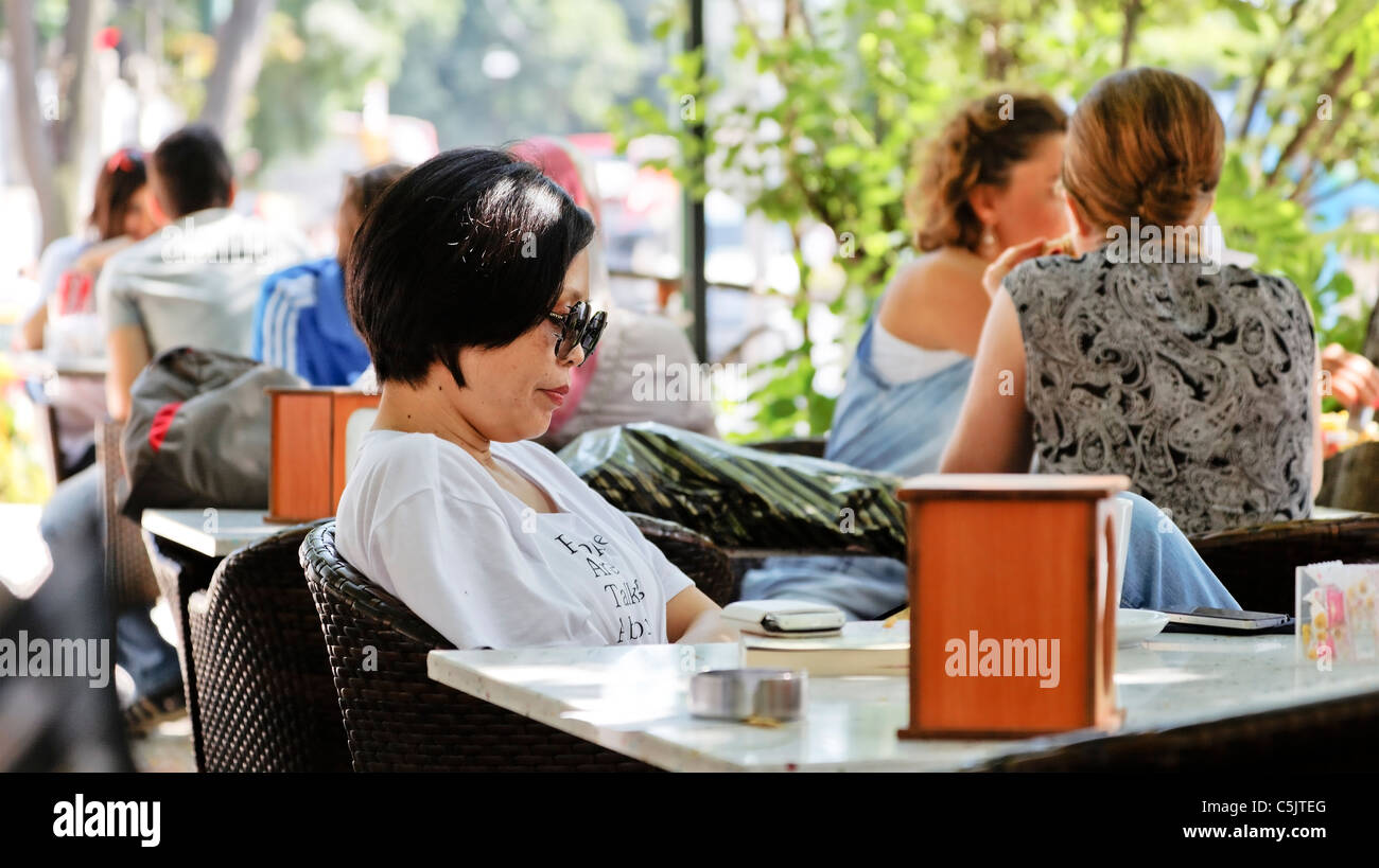Juni 2011 saß Frau mit Sonnenbrille am Tisch outdoor-Café Istanbul Türkei. Weitere Gönner, Landschaft textfreiraum Ernte Bereich Stockfoto