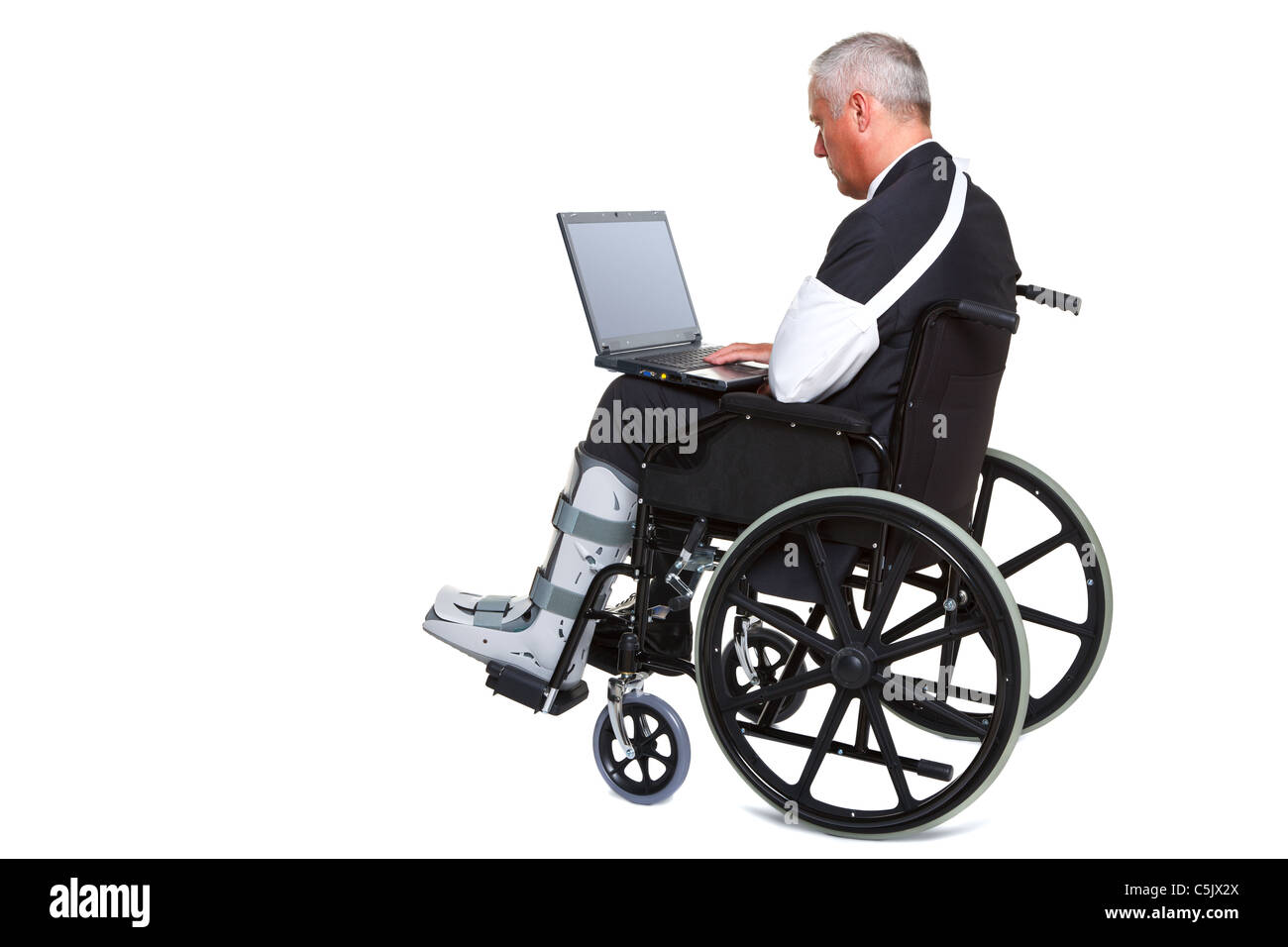 Foto von einem verletzten Geschäftsmann sitzt in einem Rollstuhl arbeitet an einem Laptop-Computer, auf dem weißen Hintergrund isoliert. Stockfoto