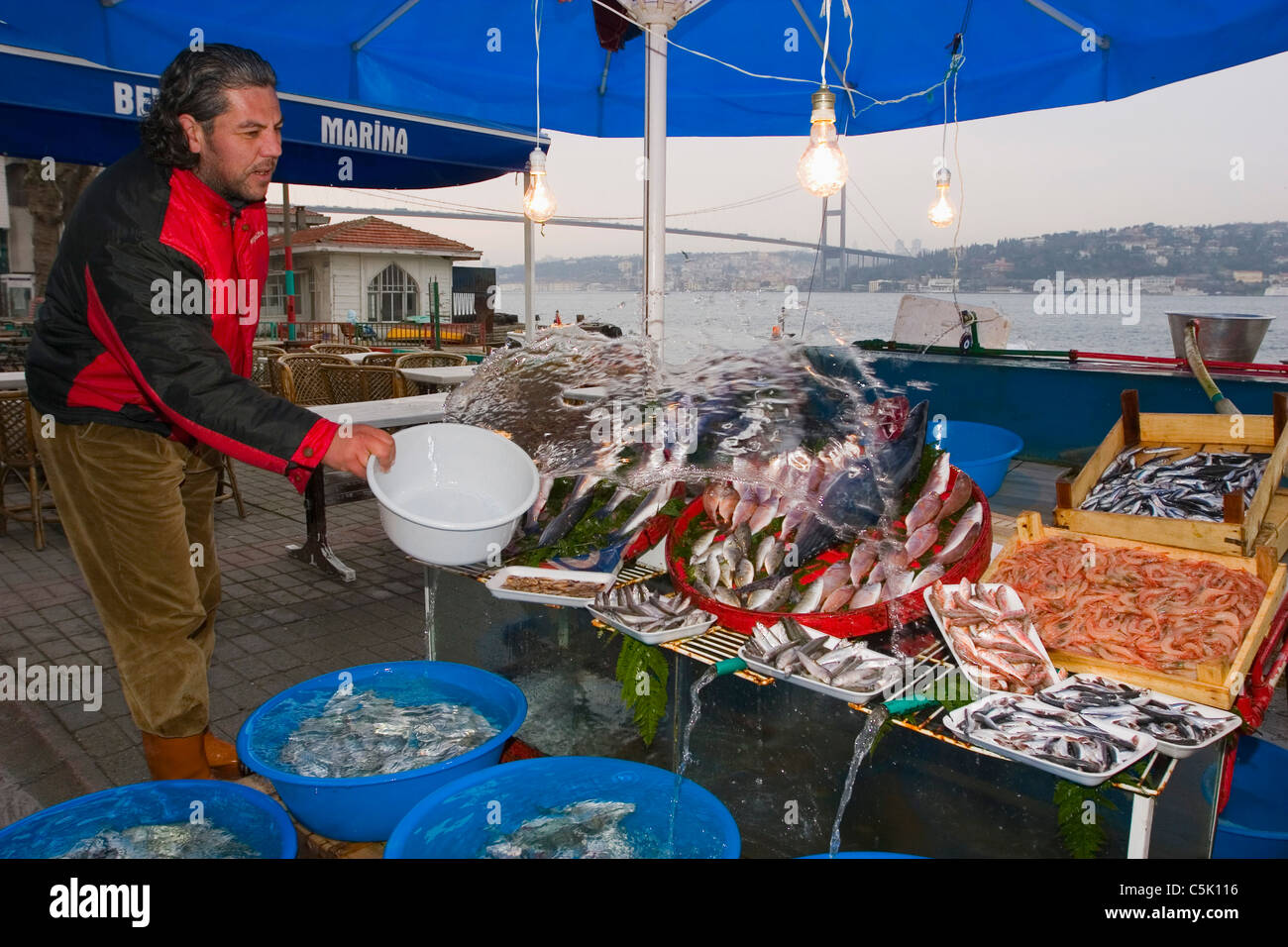 Fischhändler gießt Wasser über die Fische auf dem Display in Beylerbeyi, Istanbul, Türkei Stockfoto