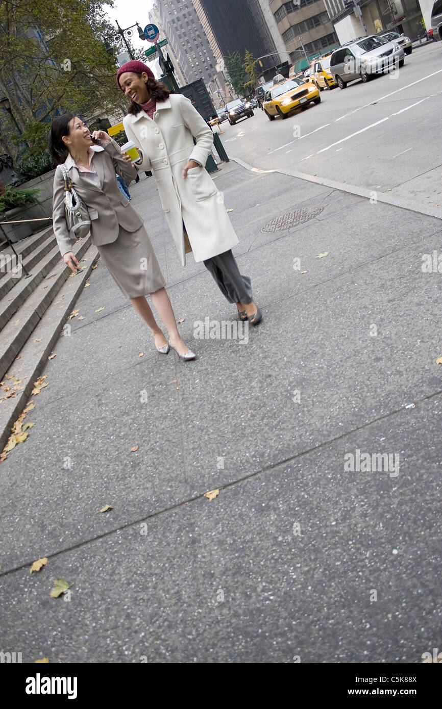 Zwei Business-Frauen in der Großstadt mit viel textfreiraum wandern. Eine Frau wird auf ihrem Handy. Stockfoto