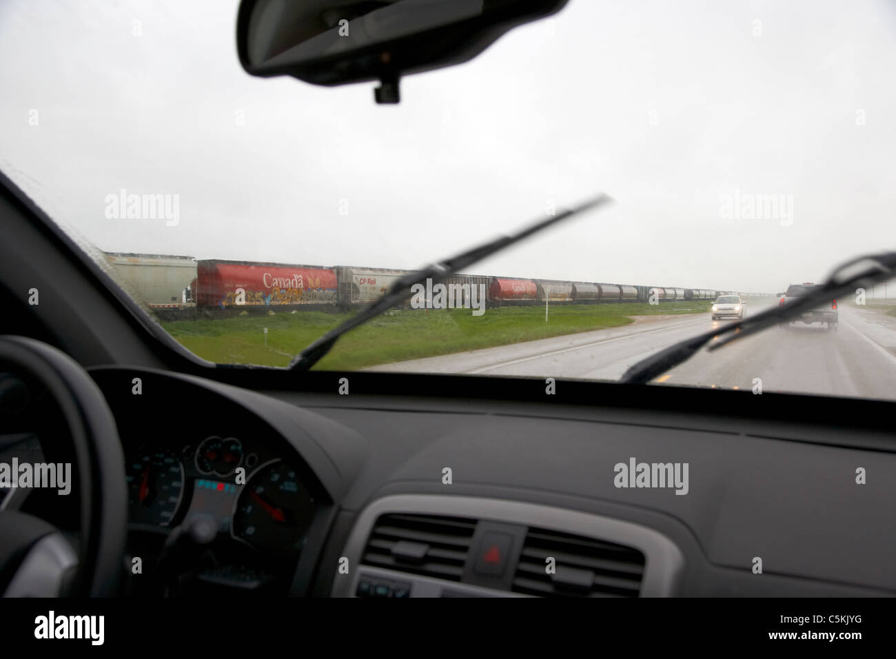 Auto fahren durch schwere Gewitter vorbei Zug im südlichen Saskatchewan Kanada Stockfoto