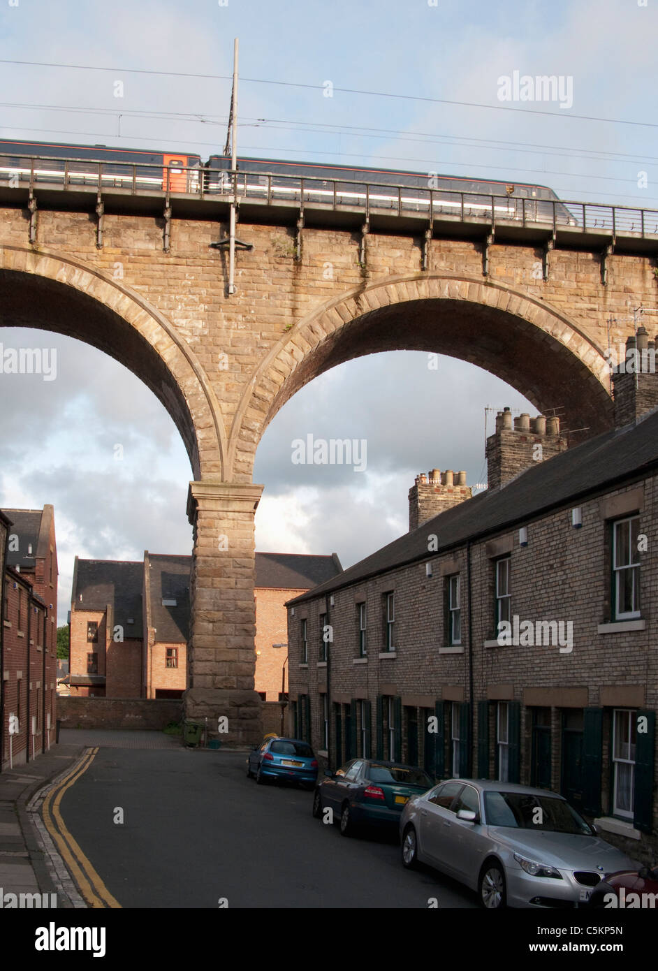 Trainieren Sie, überqueren ein Eisenbahnviadukt über eine kleine Straße von Reihenhäusern, Durham, County Durham, England, UK Stockfoto