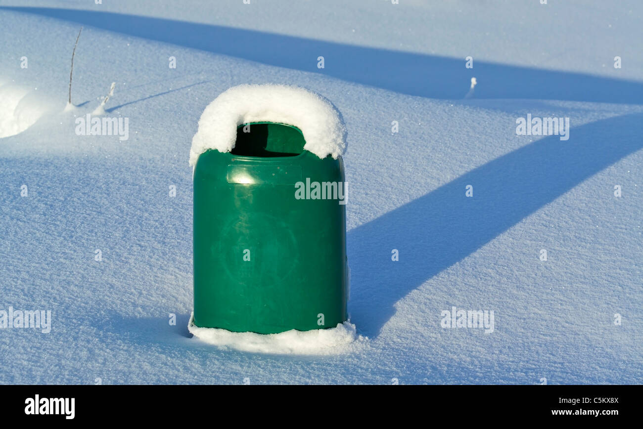 grüne Kunststoff Mülleimer teilweise begraben im Schnee Stockfoto