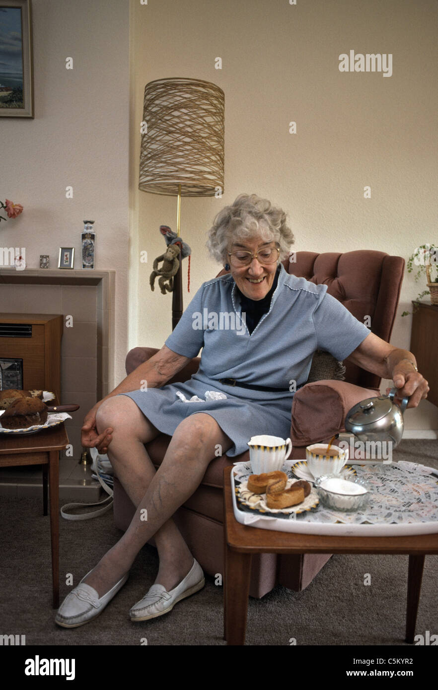 ältere Frau serviert Tee und Kuchen zu Hause Stockfoto