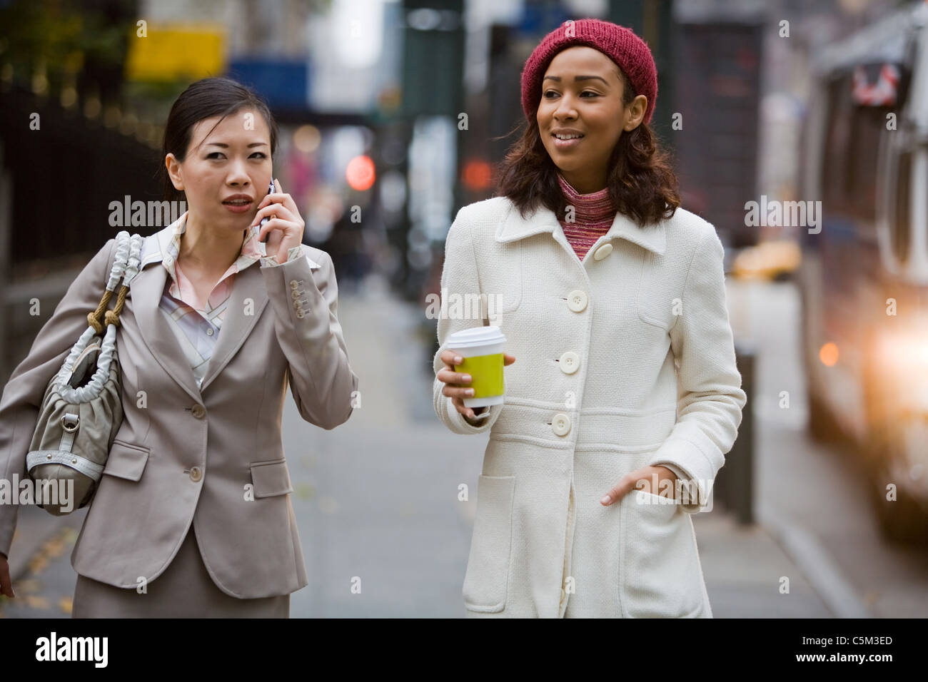 Zwei Business-Frauen in der großen Stadt zu Fuß. Man ist auf ihrem Handy. Stockfoto