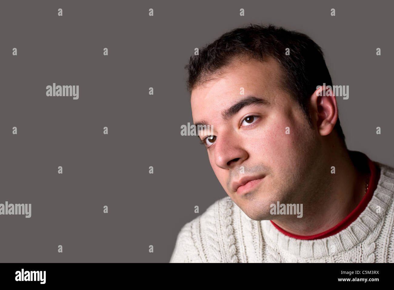 Ein junger Mann denken über etwas über silbernem Hintergrund isoliert. Stockfoto