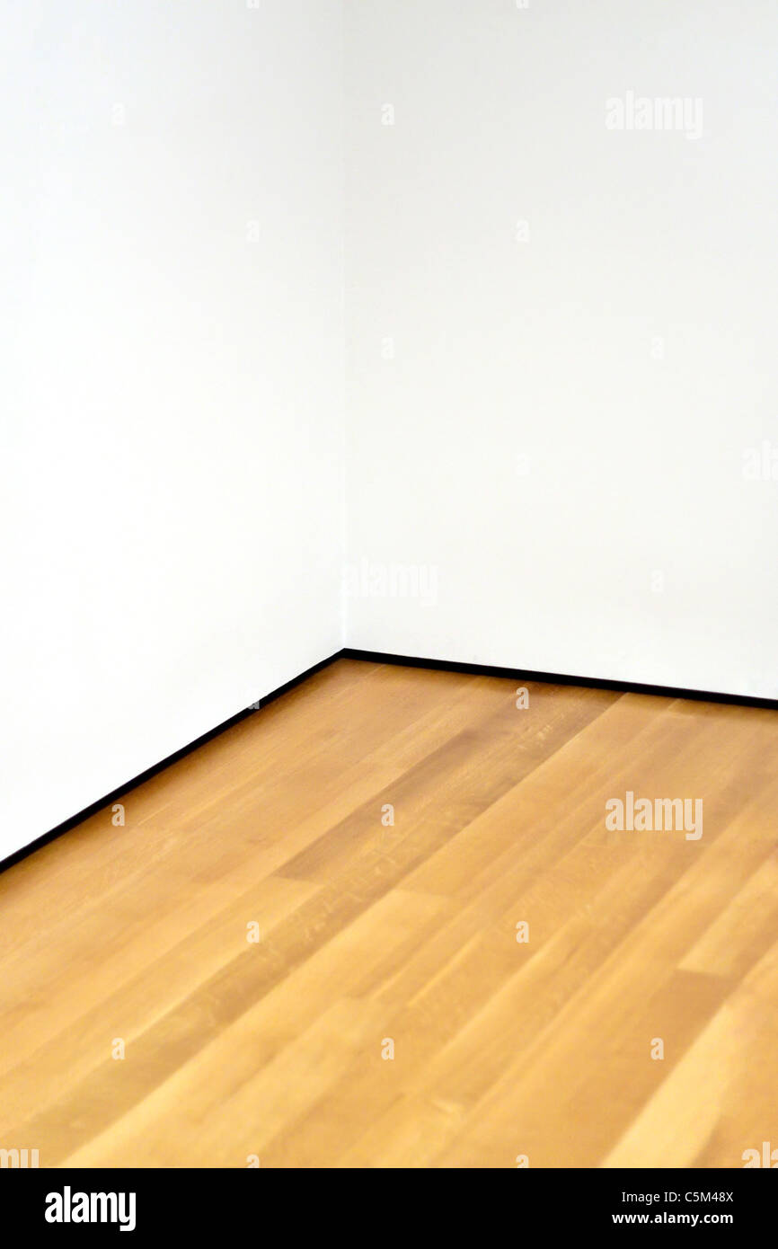 Die Ecke von einem leeren Raum mit Holzboden und weiße Wände. Es gibt viele Textfreiraum. Stockfoto